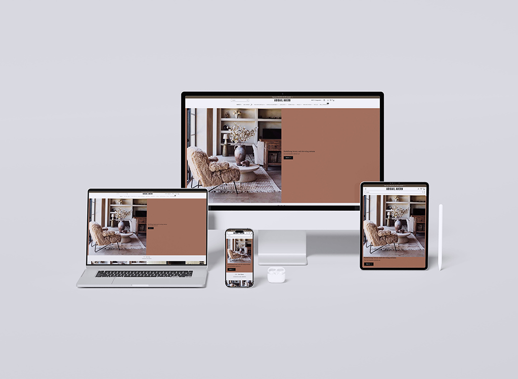A collection of devices including a desktop, laptop, tablet, and smartphone displaying a modern interior design website featuring a cozy living room with a stylish chair and decorative elements.
