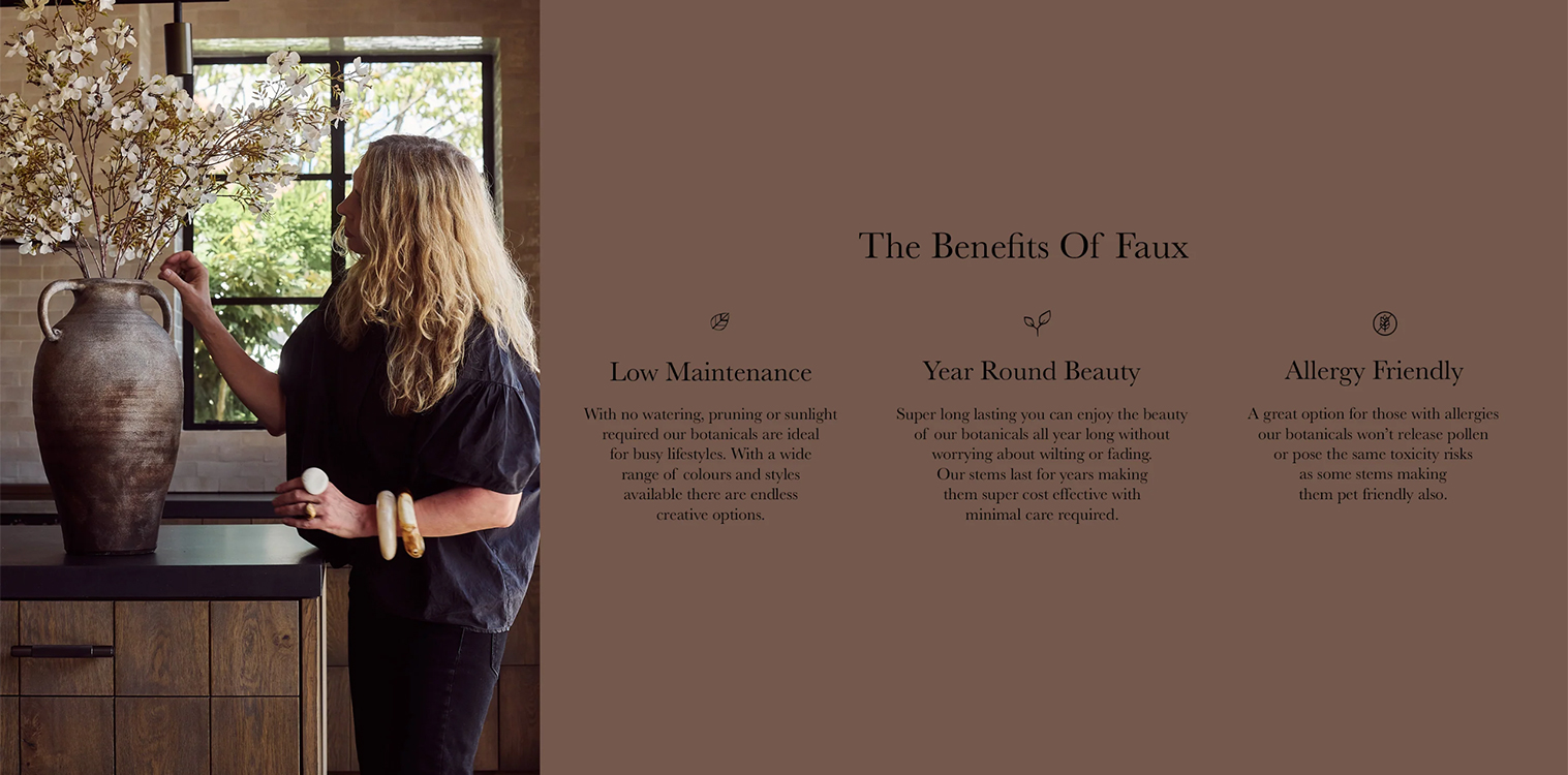 Woman arranging faux flowers in a decorative vase on a kitchen countertop, highlighting the benefits of faux botanicals, including low maintenance, year-round beauty, and allergy-friendly features.
