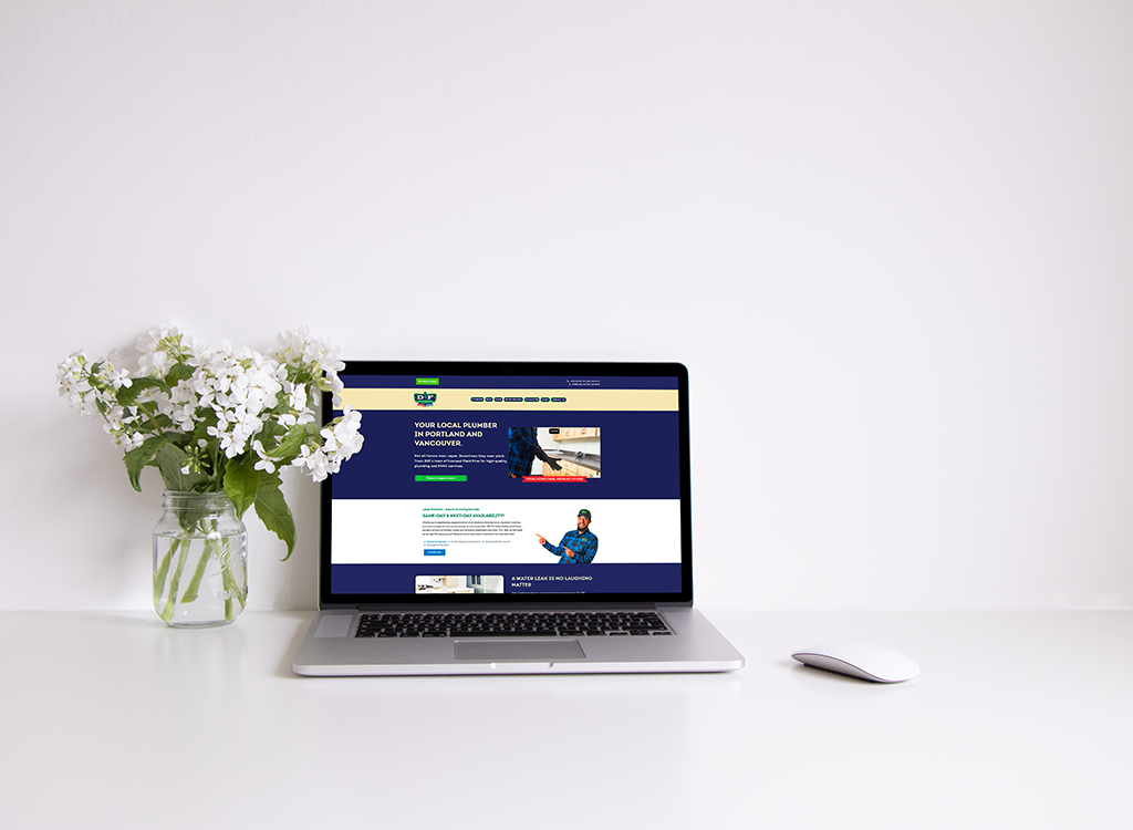 Laptop displaying a plumbing service website for local plumbers in Portland and Vancouver, with a vase of white flowers on a clean desk.