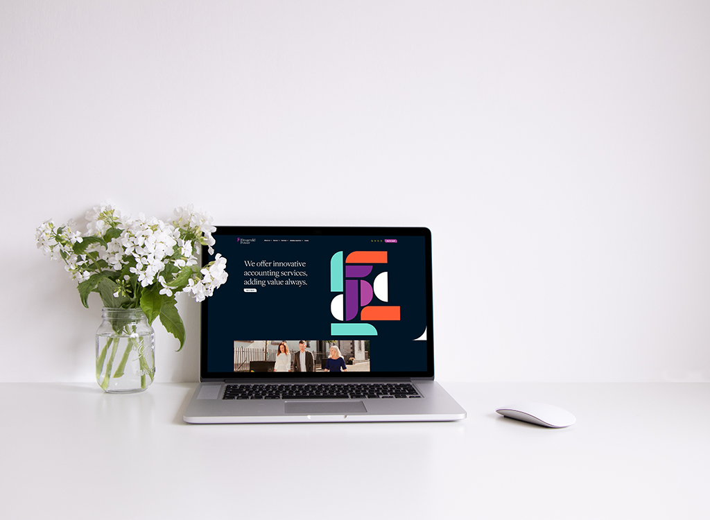 Laptop displaying a modern website offering innovative accounting services, alongside a vase of white flowers on a clean desk. The site features colorful graphics and a professional layout, emphasizing value addition.