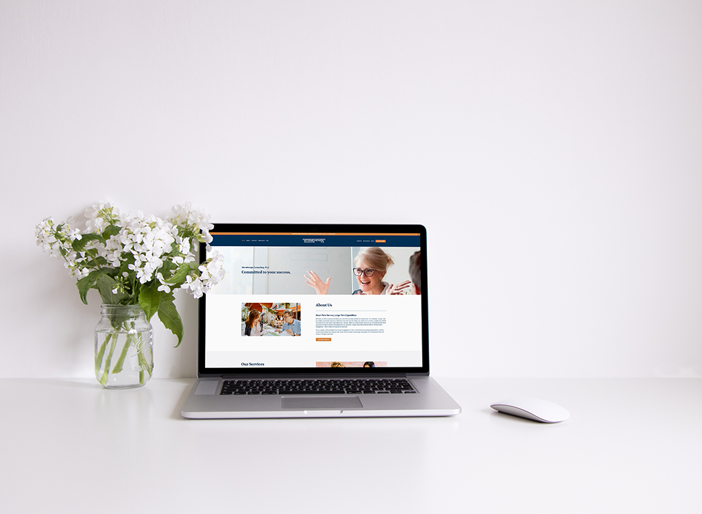A modern workspace featuring a laptop displaying a professional website, accompanied by a vase of white flowers, creating a clean and inviting atmosphere for remote work or online business.