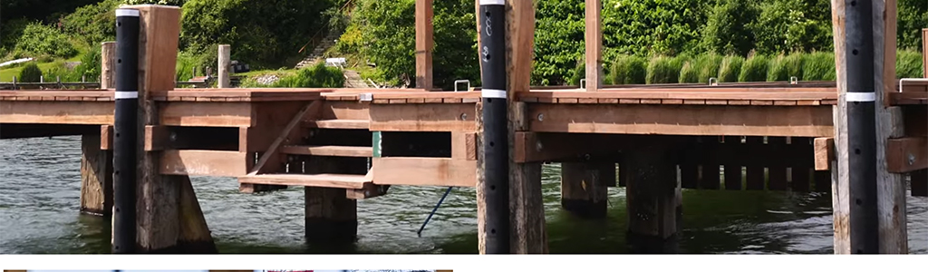 Wooden dock extending over calm water, featuring steps for access, surrounded by lush greenery and trees. Ideal for fishing or leisure activities.